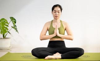 donna che fa yoga plancia sul tappetino yoga verde per meditare ed esercitare in casa. foto