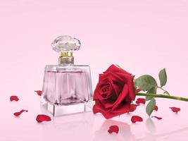 bottiglia di profumo con fiori di rosa su sfondo rosa foto