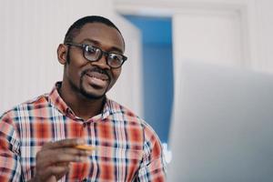 l'uomo afro positivo con gli occhiali ha una conferenza online sul pc. insegnamento a distanza. corsi online. foto