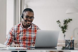 lo studente maschio afroamericano che indossa la cuffia impara la lingua online sul laptop. Educazione a distanza foto