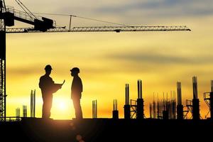 silhouette dell'architetto che lavora sui lavoratori del cantiere all'ora del tramonto. foto