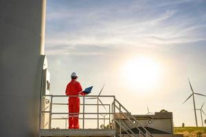 ingegnere uomo che lavora e tiene il laptop per controllare le prestazioni della stazione del generatore di energia dell'azienda agricola di turbine eoliche, concetto di risorse sostenibili, concetto di professionista per l'industria energetica foto