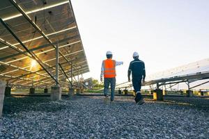 la vista dal basso del tecnico cammina con l'investitore attraverso il campo dei pannelli solari, l'energia alternativa per conservare l'energia mondiale, l'idea del modulo fotovoltaico per la produzione di energia pulita foto