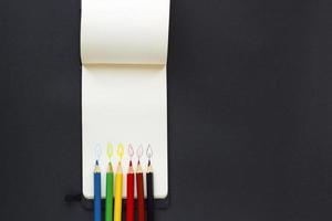 fiamma di candela disegnata con fila di matite colorate su un foglio di quaderno bianco. idea per congratulazioni, vacanze, compleanno. concetto di lavoro con spazio di copia foto
