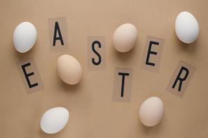 uova di Pasqua su sfondo marrone pastello con scritte. vista dall'alto. disteso. concetto minimo foto