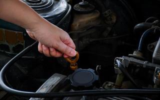 una donna controlla l'olio motore di una vecchia auto parcheggiata in garage prima di partire, pulendo l'auto prima di mettersi in viaggio. foto