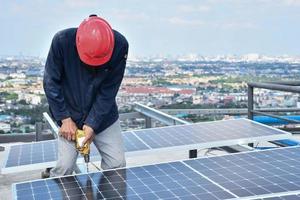 il tecnico sta facendo i fori per montare la cella del pannello solare con trapano elettrico foto