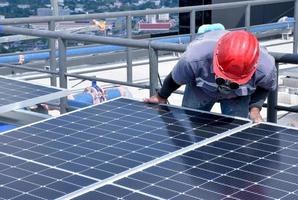 il tecnico installa la cella del pannello solare con trapano elettrico sulla sommità del tetto. foto