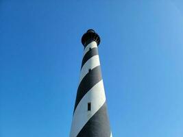 alto edificio del faro a strisce bianche e nere con cielo blu foto