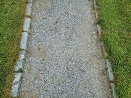 sentiero in pietra grigia o ghiaia con erba verde o prato foto
