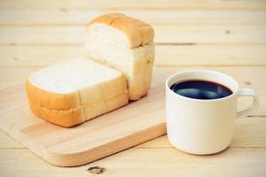 tazza di caffè e pane sul pavimento di legno foto