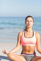 donna adatta che fa yoga vicino al mare