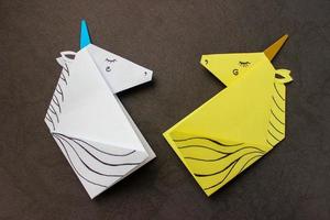 unicorni bianchi e gialli realizzati con la tecnica dell'origami su sfondo nero. foto