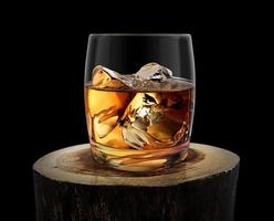 bicchiere di whisky sul vecchio ceppo di legno, sfondo nero foto