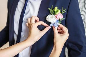 la sposa corregge il fiore all'occhiello dello sposo al loro matrimonio foto
