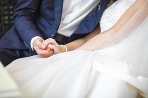 lo sposo abbraccia la sposa con il bouquet da sposa. le mani degli sposi novelli foto