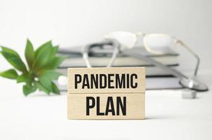 Parola del piano pandemico scritta su blocchi di legno accanto a uno stetoscopio foto