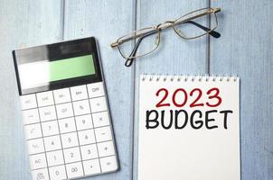 budget 2023 parola sul taccuino con calcolatrice e occhiali foto