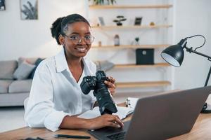 seduto a tavola. la giovane donna afroamericana in camicia bianca è a casa foto