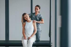 esercizi per il collo. la donna è in centro sanitario e viene aiutata dal medico foto