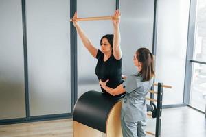 esercizio di stretching. la donna è in centro sanitario e viene aiutata dal medico foto