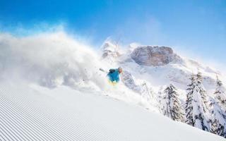sciatore che scia in discesa in alta montagna foto