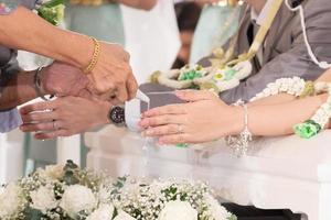 mani che versano acqua di benedizione nella cerimonia di versamento dell'acqua foto