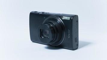 foto di una fotocamera tascabile vintage con obiettivo aperto su sfondo bianco.