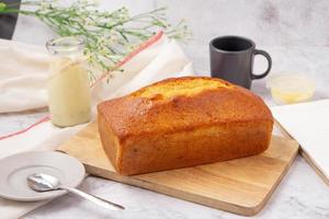 libbra di torta con glassa al limone sul tagliere, latte in bottiglia di vetro. foto