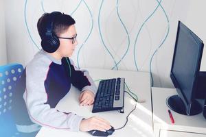 ragazzo adolescente che indossa gli auricolari guardando il monitor del computer. concetto di apprendimento a distanza. foto