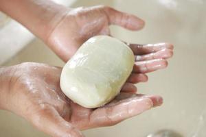 giovane che si lava le mani con acqua calda e sapone foto