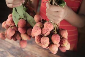 giovani uomini in possesso di frutta litchi da vicino foto