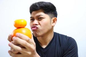 uomo asiatico attraente che mangia arance. isolato su sfondo bianco foto