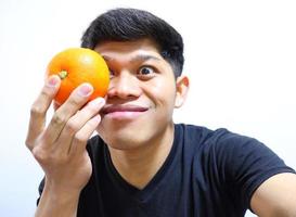 uomo asiatico attraente che mangia arance. isolato su sfondo bianco foto