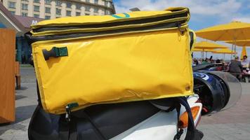 scooter di consegna corriere con zaino giallo. un corriere su uno scooter è in attesa di un ordine. consegna rapida della merce ai clienti dal ristorante e dal negozio. copia spazio sulla borsa. foto