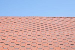 nuovo tetto con tegole rosse contro il cielo blu. foto di alta qualità. tegole sul tetto della casa. utilizzare per pubblicizzare la fabbricazione e la manutenzione del tetto. trama maculata. coperture convenienti.