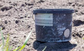 secchio da giardino sporco di plastica, contenitore con manico su orto su terreno sciolto. attrezzatura da giardino. luminosa giornata di sole in giardino. foto