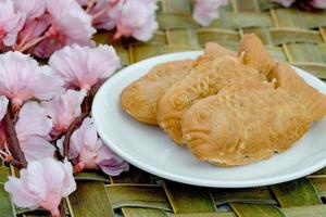 torte taiyaki in piatto bianco con fiori di ciliegio, pasticceria giapponese foto