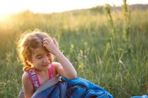 la ragazza è insoddisfatta delle punture di zanzara graffiante, il bambino dorme in un sacco a pelo sull'erba in campeggio. attività ricreative all'aperto ecologiche, ora legale. disturbi del sonno, repellente. foto