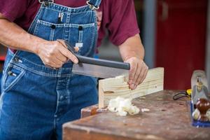 un falegname lavora con attrezzature su un tavolo di legno in una falegnameria. foto