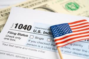 modulo di dichiarazione dei redditi 1040 con bandiera usa america e banconota in dollari, reddito individuale statunitense. foto