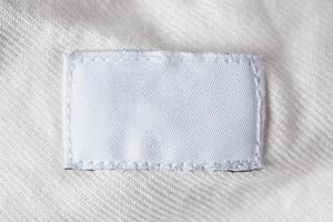 etichetta di vestiti per la cura del bucato in bianco bianco sulla camicia di cotone foto
