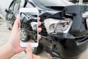 smartphone mobile della tenuta femminile che fotografa l'incidente d'auto foto