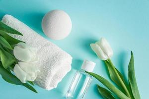 prodotti per la cura della pelle su sfondo blu. cosmetici naturali e tulipani bianchi. foto