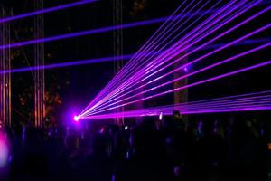 raggi al neon laser viola. folla di persone che guardano lo spettacolo laser al festival di strada. foto
