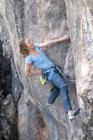 la ragazza sportiva è impegnata nell'arrampicata su roccia foto