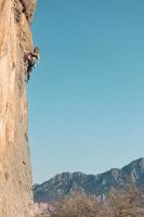 la ragazza sportiva è impegnata nell'arrampicata su roccia foto