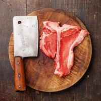 bistecca con l'osso di carne cruda e mannaia foto