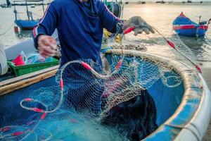 pescatore che getta la sua rete all'alba o al tramonto. i pescatori tradizionali preparano la rete da pesca foto