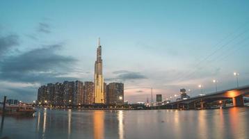 città di ho chi minh, vietnam, 11 febbraio 2022 vista del tramonto al punto di riferimento 81 - è un grattacielo super alto e un ponte saigon con edifici di sviluppo lungo il fiume saigon la luce si attenua foto